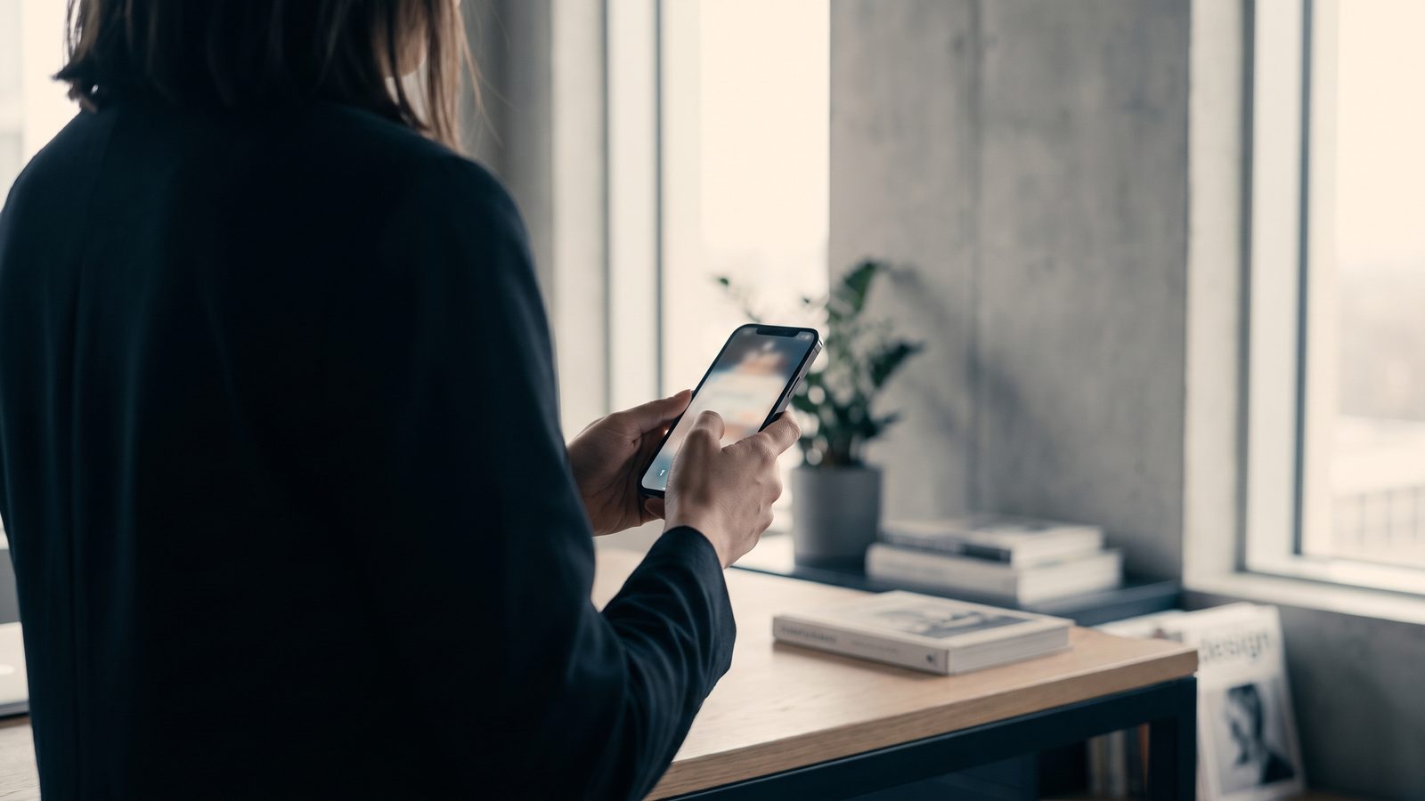 A person in a modern office holding a phone, weighing an AI assistant's recommendation